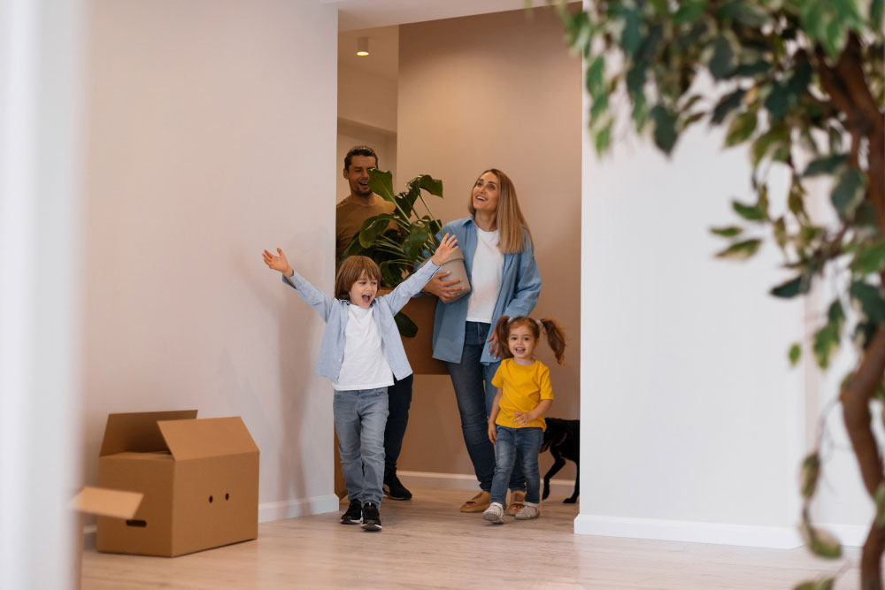 Jak vybrat nájemníka: Šťastně vypadající rodina se dvěma dětmi vcházející do nového bytu nebo domu.